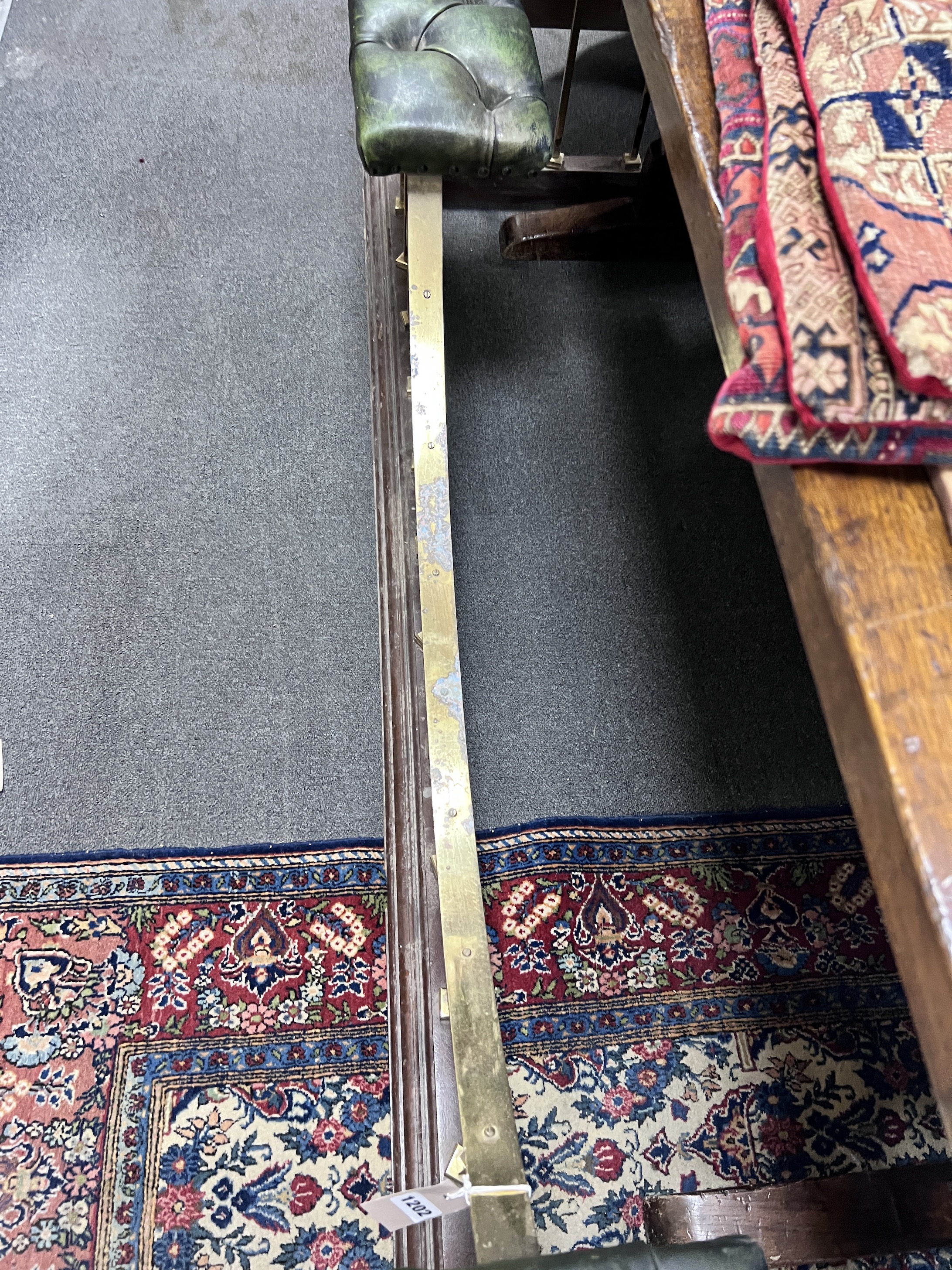 An Edwardian style brass and hardwood club fender, with simulated buttoned leather top, width 235cm, height 52cm